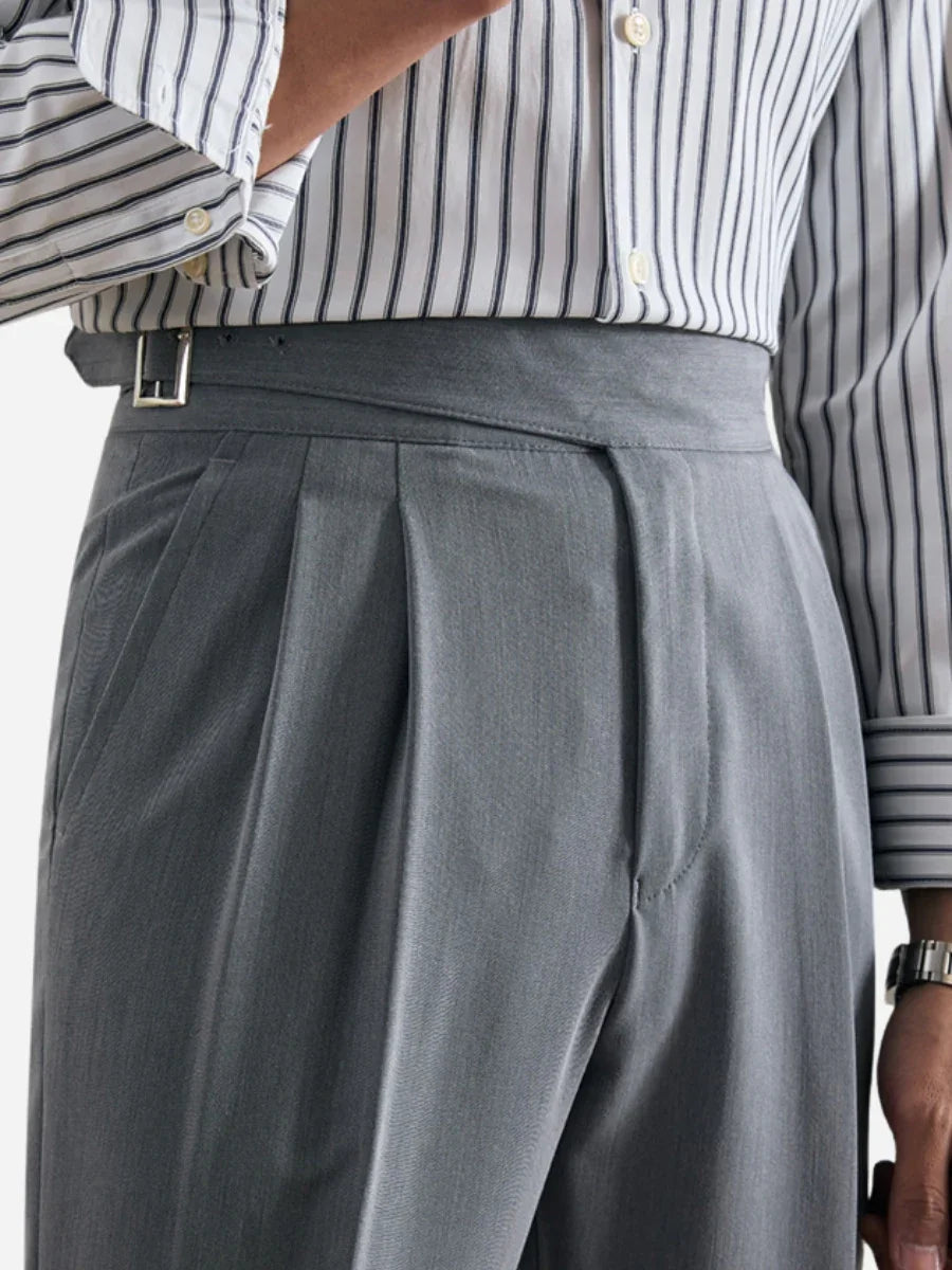 Close-up of man wearing gray pleated dress pants with side adjuster belt and striped shirt