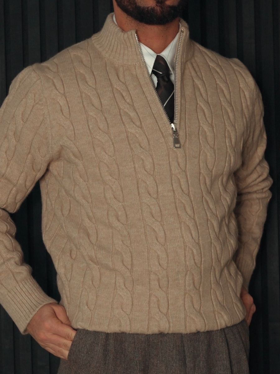 Man wearing beige cable knit half-zip sweater with white shirt, black tie, and gray trousers