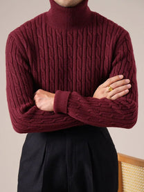 Person wearing a burgundy cable knit sweater against a neutral background