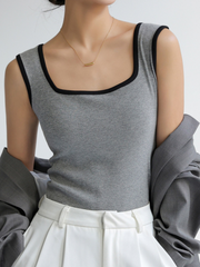 Wide-Edge Tank Top from Marini's Old Money Collection in gray with black trim, styled with white trousers and a delicate necklace.
